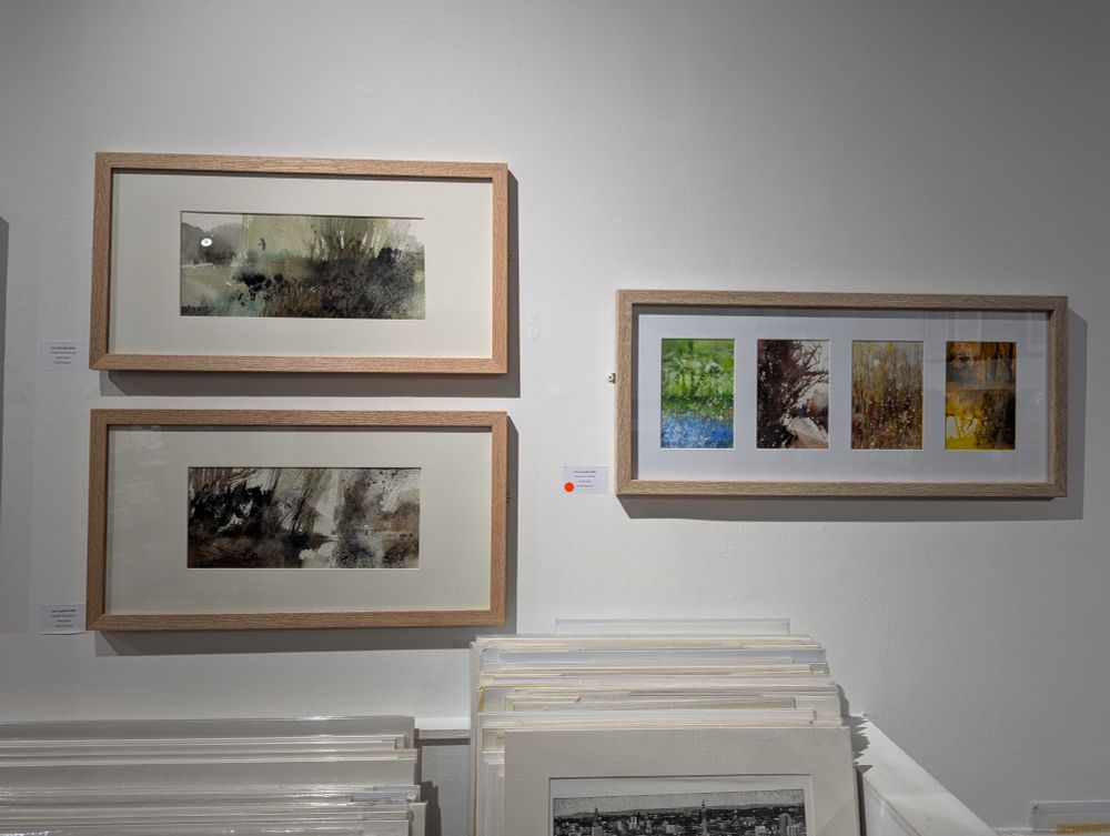 Collection of 3 framed watercolour paintings by RWS member Sue Howells on display at Bankside Gallery. On left are two horizontal landscapes in semi-abstract style. On right is a framed collection of 4 small paintings representing the seasons. https://www.royalwatercoloursociety.co.uk/ Photo by Ellen Friedman