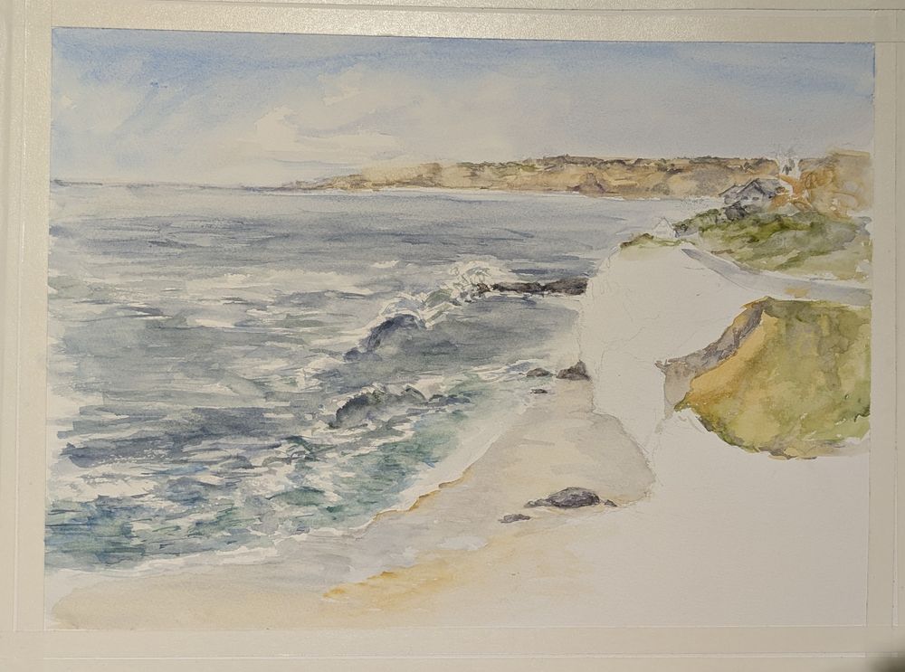 Unfinished watercolor painting of blue and green ocean, white foam and waves crashing on rocks and Beach. In the distance are cliffs.
Right hand side of painting with the near cliffs has not been done yet. 
Painting by Ellen Friedman