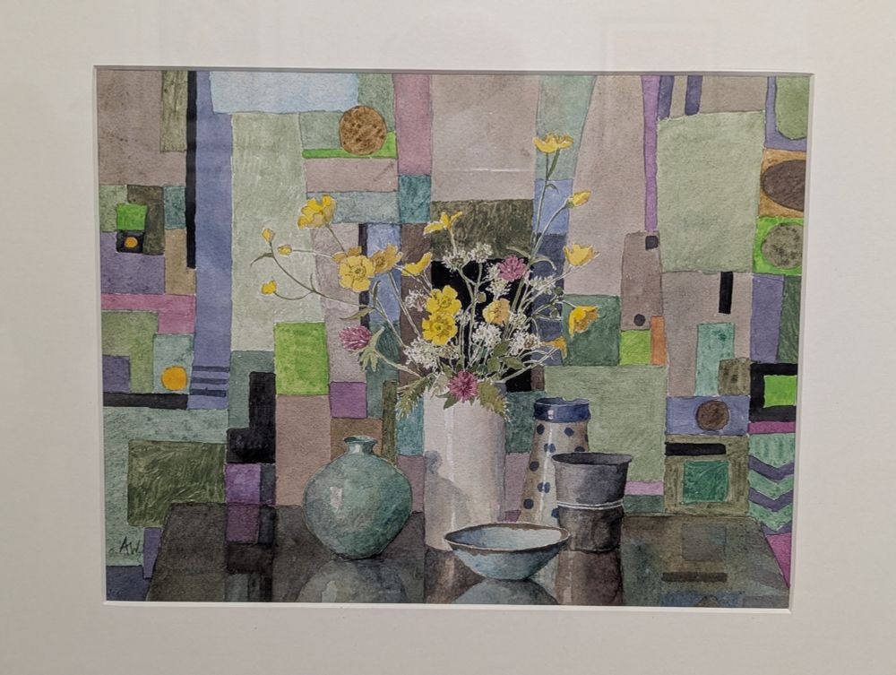 Watercolour painting by RWS member Annie Williams on display at Bankside Gallery London. This painting is a still life with 5 pottery vases and bowls plus an arrangement of flowers especially yellow and pink blooms shown against a multi-coloured background of geometric shapes. https://www.royalwatercoloursociety.co.uk/ Photo by Ellen Friedman