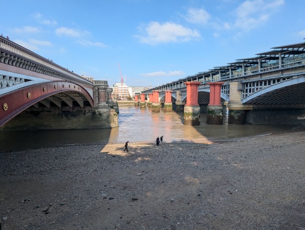A view across the river Thames in London etween the Blackfriars Bridges. Large construction cranes can be seen atop a building on the far bank. Photo by Ellen Friedman Oct 2025