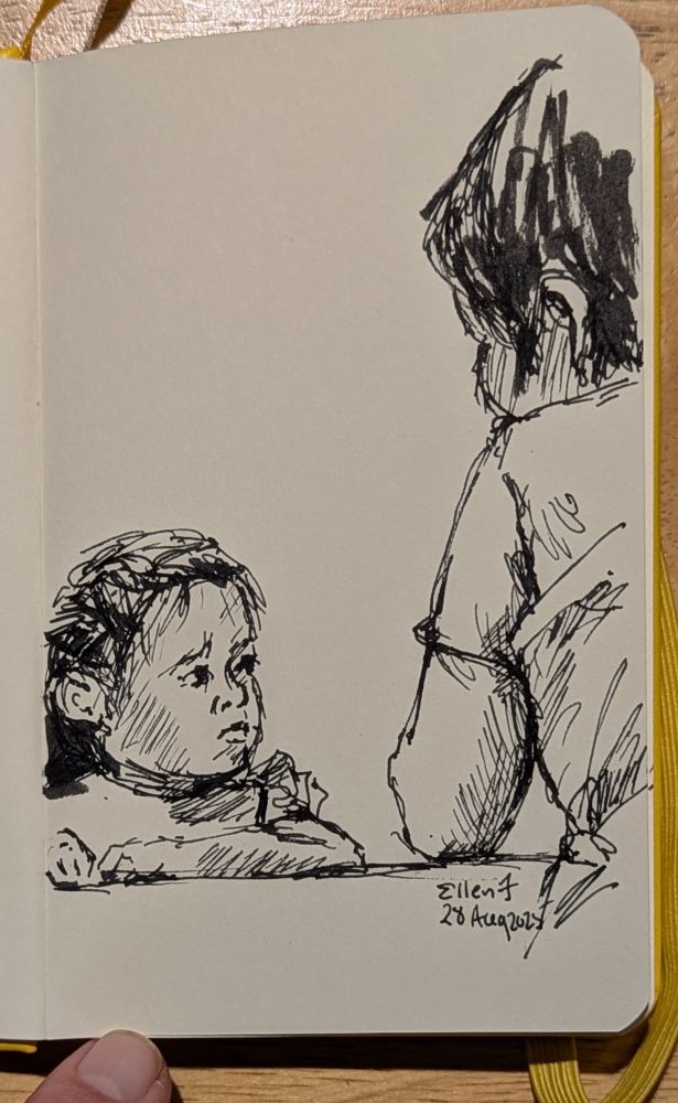 Very small black ink sketch of little girl on left at a table, looking up pensively at an adult who is resting her arm on table. Drawing by Ellen Friedman