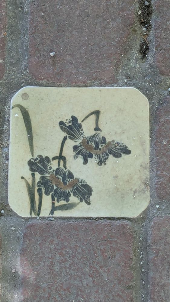 Painted tile inset into brick courtyard. Tile shows an iris. Photo by Ellen Friedman