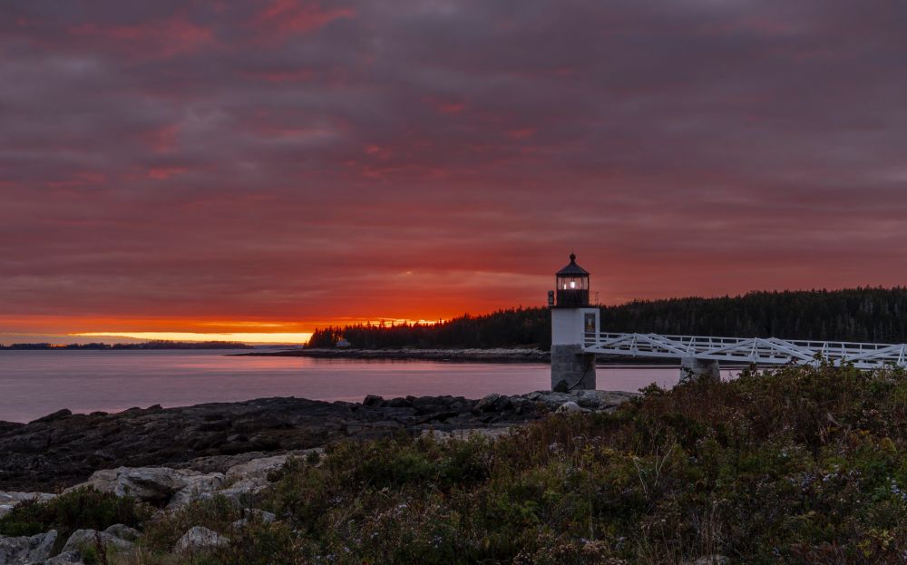 sunset in the background of a lighthouse in maine