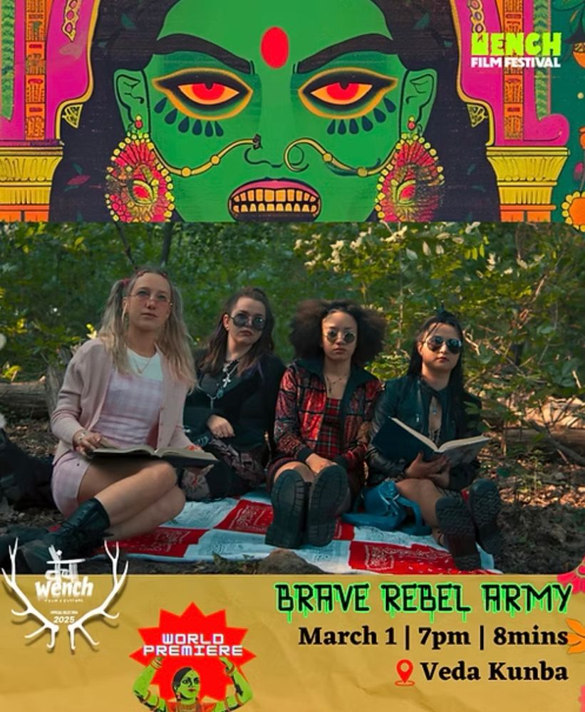 Four young women, dressed in 90’s clothing and wearing sunglasses, sit on a picnic blanket in a park. All are holding open books while looking into the distance. 
