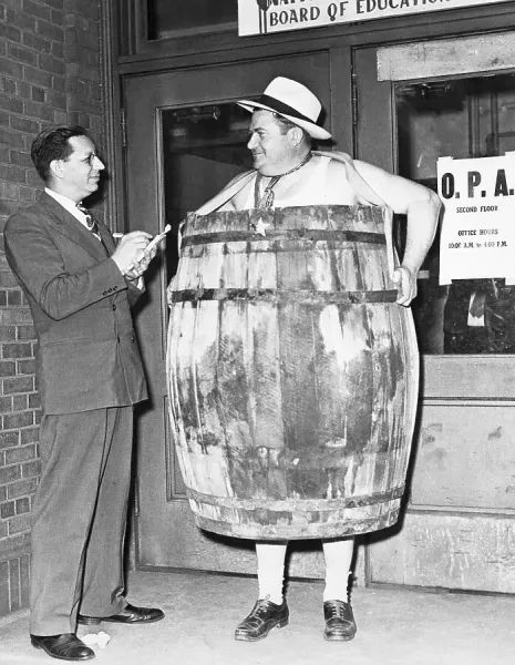 “Sheriff Kirk S. King pickets in a wooden barrel outside the Winnebago Price and Rationing Board. The town sheriff, who stands at six-foot-two, claims that local men's clothing stores cannot outfit him due to OPA regulations. Edwin Kotche, chief clerk of Rockford's OPA board, takes notes on the situation.” https://www.fineartstorehouse.com/bettmann-archive/man-wearing-barrel-demonstration-39317127.html