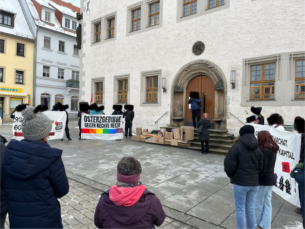 Rathaus in Dippoldiswalde mit vielen Menschen und Plakaten. Auf dem größten Plakat steht: „Osterzgebirge gegen rechte Hetze“, darunter ist ein Regenbogen gemalt.