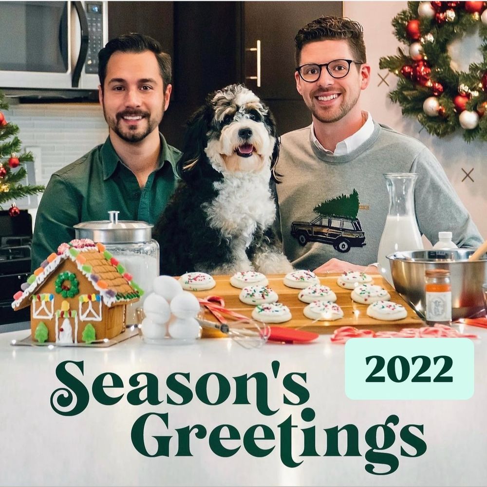 Two men posing in the kitchen with a mini bernedoodle 