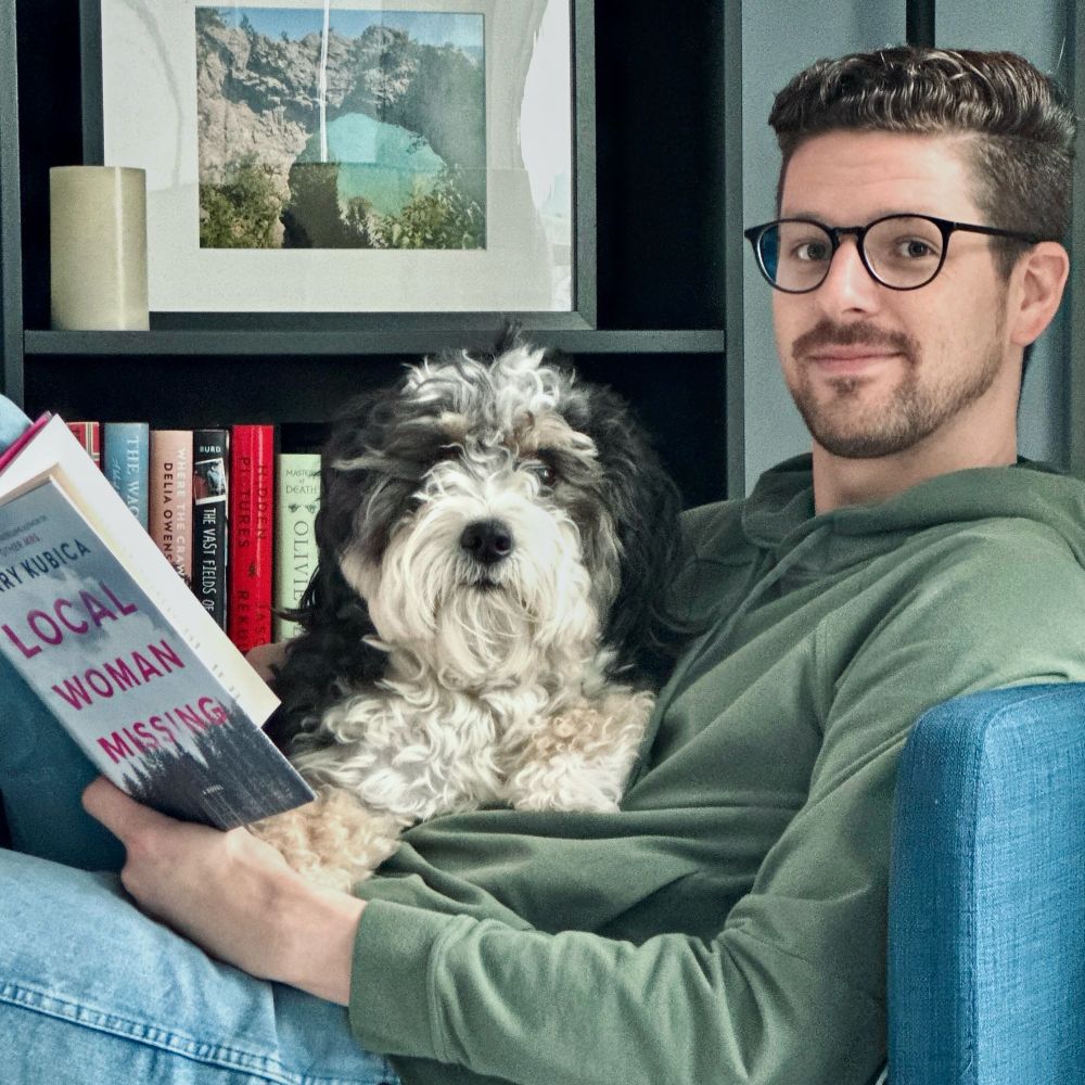 Reading a book with mini bernedoodle in lap 