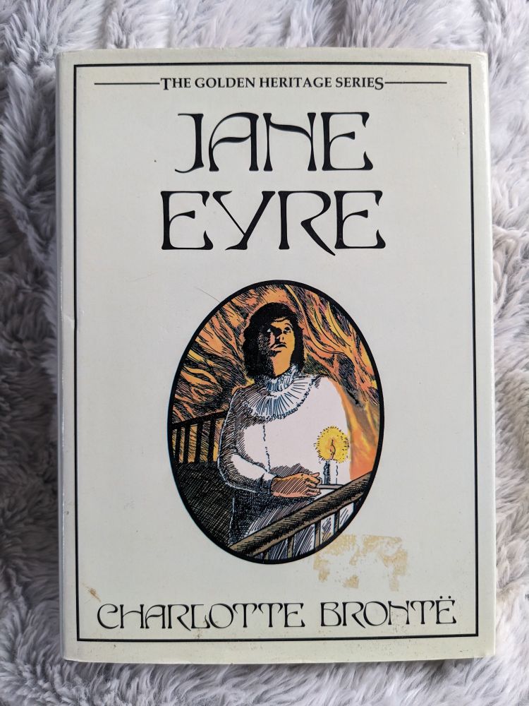 A hardback copy of the book 'Jane Eyre' by Charlotte Bronte on a fuzzy white fabric.