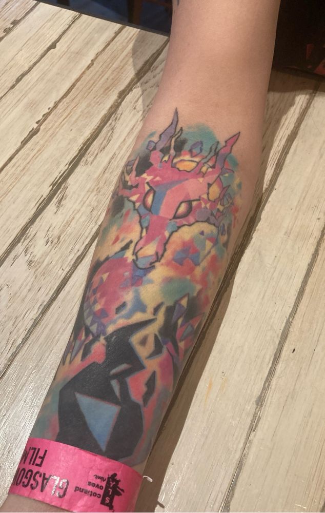 A photograph of a brightly coloured tattoo of a dragon from the film Promare