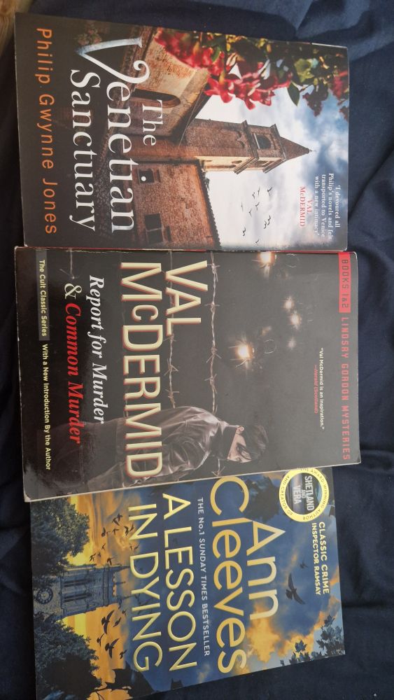 Photo of the shortlisted next options. The Venetian candidate, by Philip Gwynne Jones with a thin church tower on the cover. 

 An omnibus of Val McDermid's Report for Murder and Common murder with a person dressed in black in front of barbed wire against a night sky.  The person is looking back over their shoulder at the viewer 

And Ann Cleeves' A Lesson in Dying with an English church tower at the bottom of the page and a sunset and birds.

Although taken landscape it has been posted portrait so the books are at 90°  