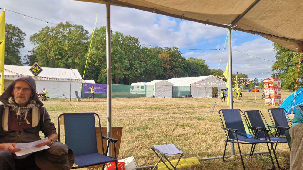 A view looking out of the Franciscan chapel temple towards some big white marquees in front of trees with a blue and white sky