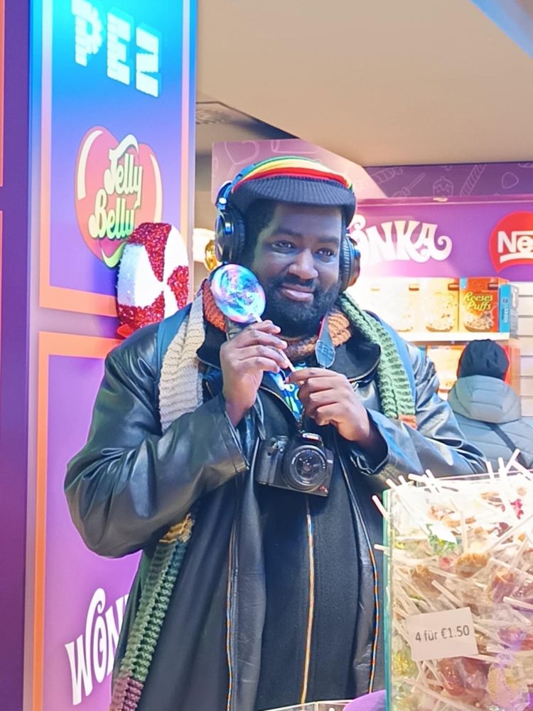 Photo de moi (oui oui de moi) souriant tenant une sucette dans une boutique de bonbon à Cologne (si mes souvenirs sont corrects)