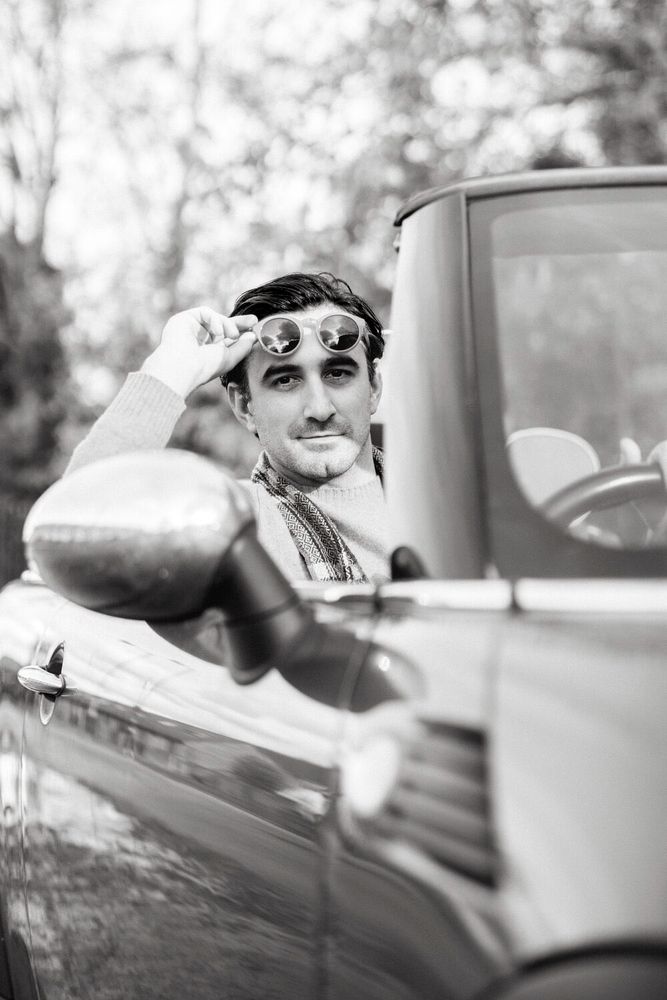 Ferdinand Kingsley in a car, in monochrome. 