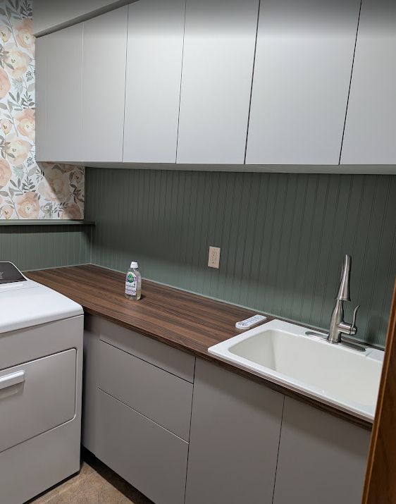 Laundry room with flower wallpaper, IKEA cabinets and countertop, green beadboard with trim, utility sink.