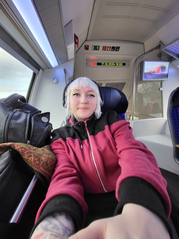 Woman with blonde bob-long hair sitting in a train with a dope jacket in a star trek design.