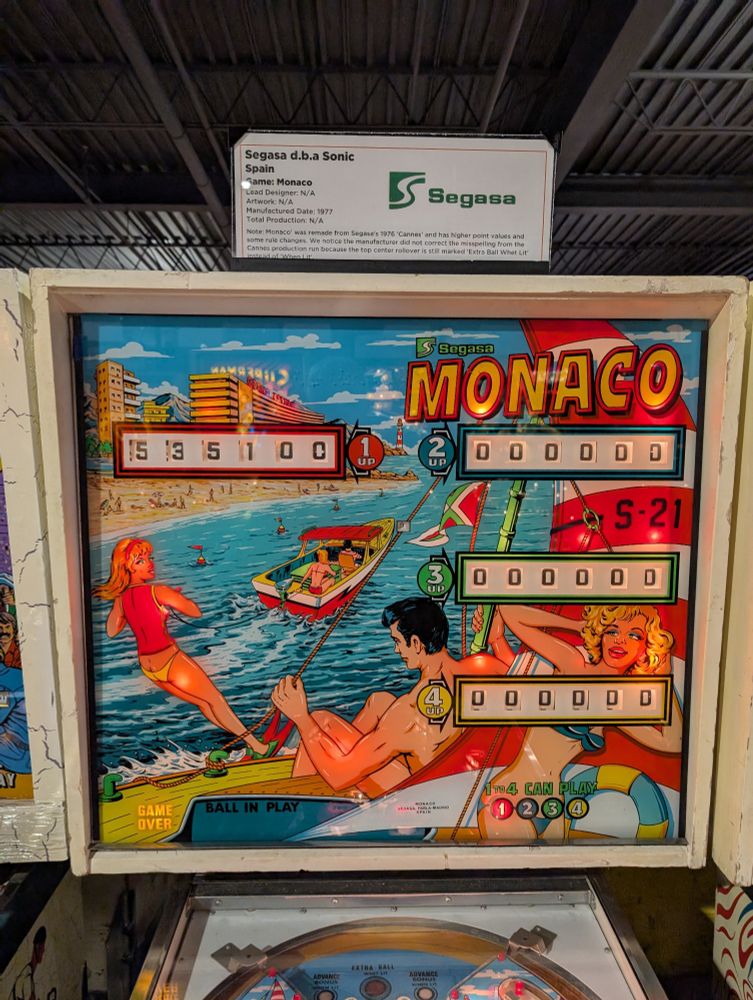 Monaco Pinball backglass.  Men and women in swimwear, boating and having fun along the coastline of a beach and hotels.