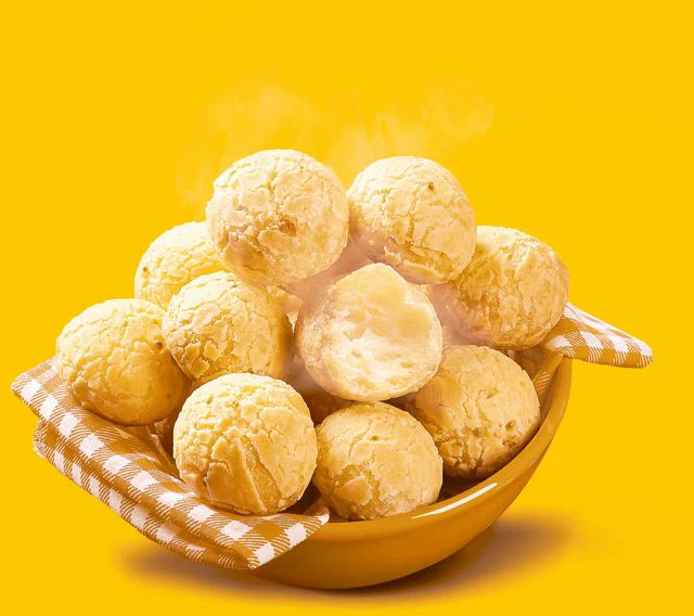 a bowl of bread balls with steam coming out of them on a yellow background