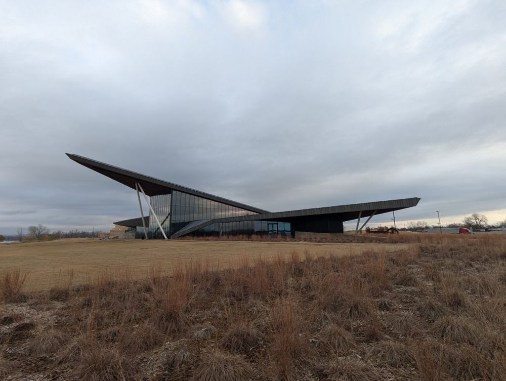 A funky looking silver building under a gray sky sits in a field in Fort Smith, Arkansas 
