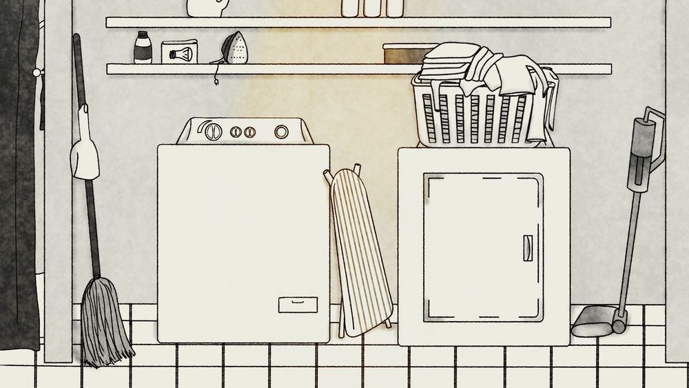 A laundry room complete (from left to right on the floor) a broom with a dustpan attached, a washer, an ironing board leaning on it, a dryer with a basket on laundry on top, and a vacuum. Above these are two long shelves. The bottom shelf (from left to right) has a bottle of cleaning stuff, a box of light bulbs, an iron, and a random shoebox sitting on top. The shelf above it has laundry detergent and three bottles of cleaning spray. 

The floor is tiles, and the whole room is attached to the bathroom. You can see a peek of the bathroom on the left side of a wall, where a towel bar and the shower curtain show. 

The whole illustration is in grey tones with some orange lighting. 