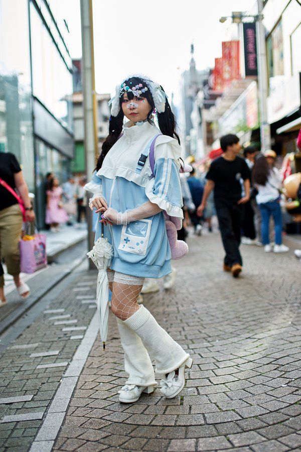 girl with pale blue and white hoodie and multiple hair clips poses in the street
