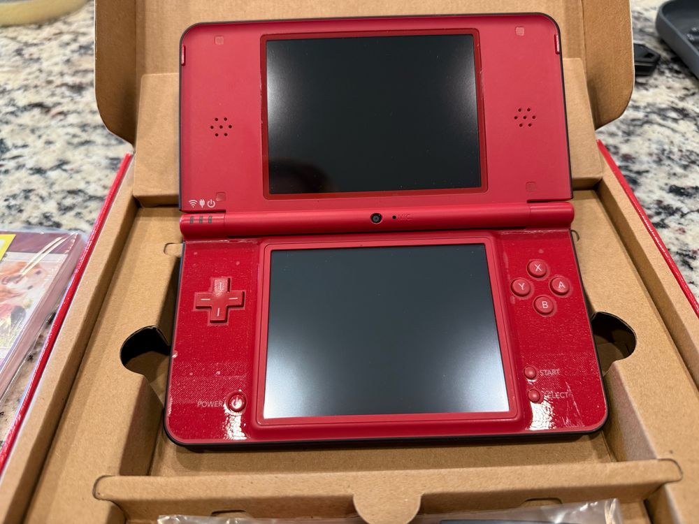 Open red Nintendo DSi XL gaming device displayed in cardboard packaging