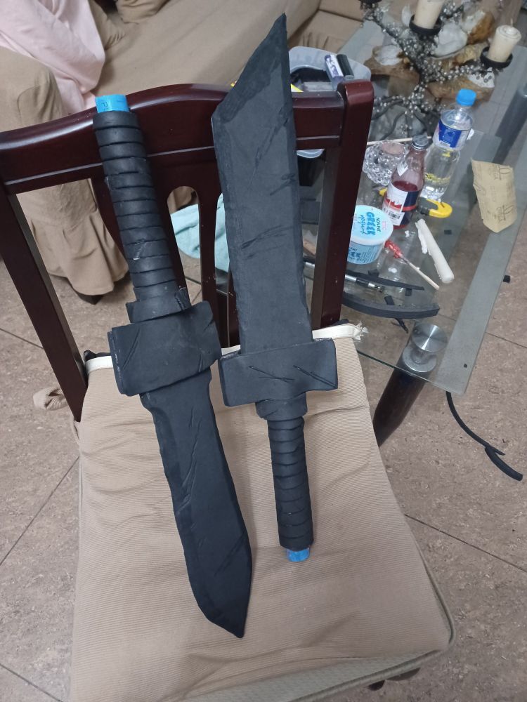 2 prop daggers on a chair with a messy table in the background