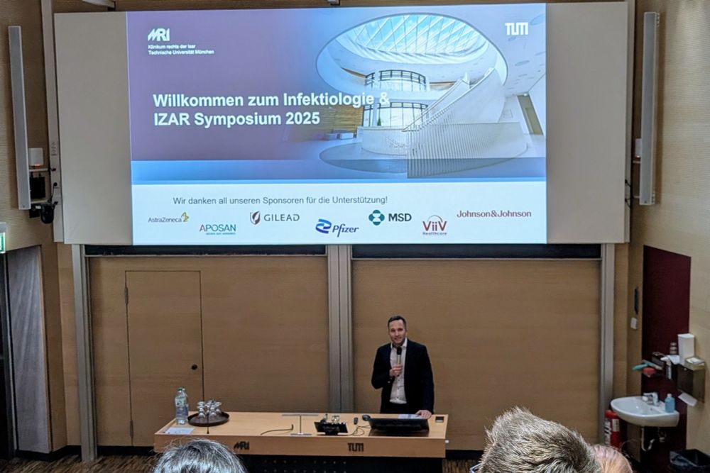 Professor Spinner steht in einem Hörsaal und spricht in ein Mikrofon 
