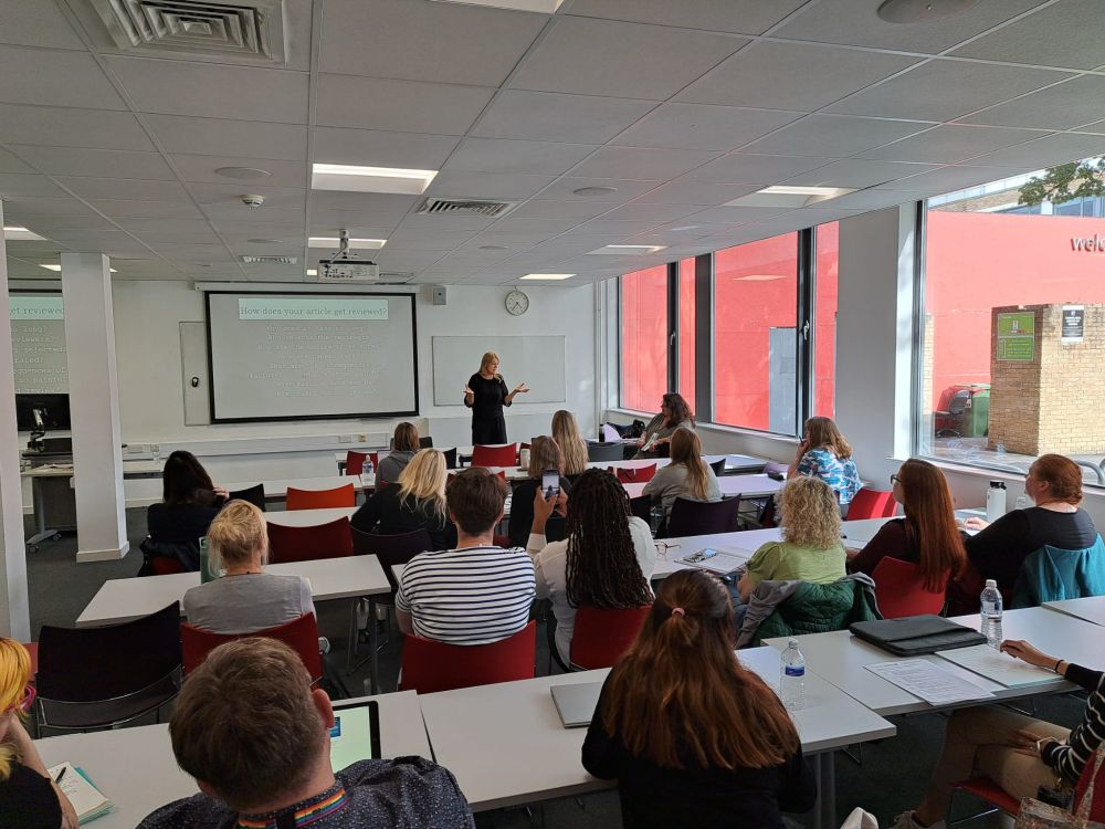 Jayne Osgood talking to a room of people in rows.