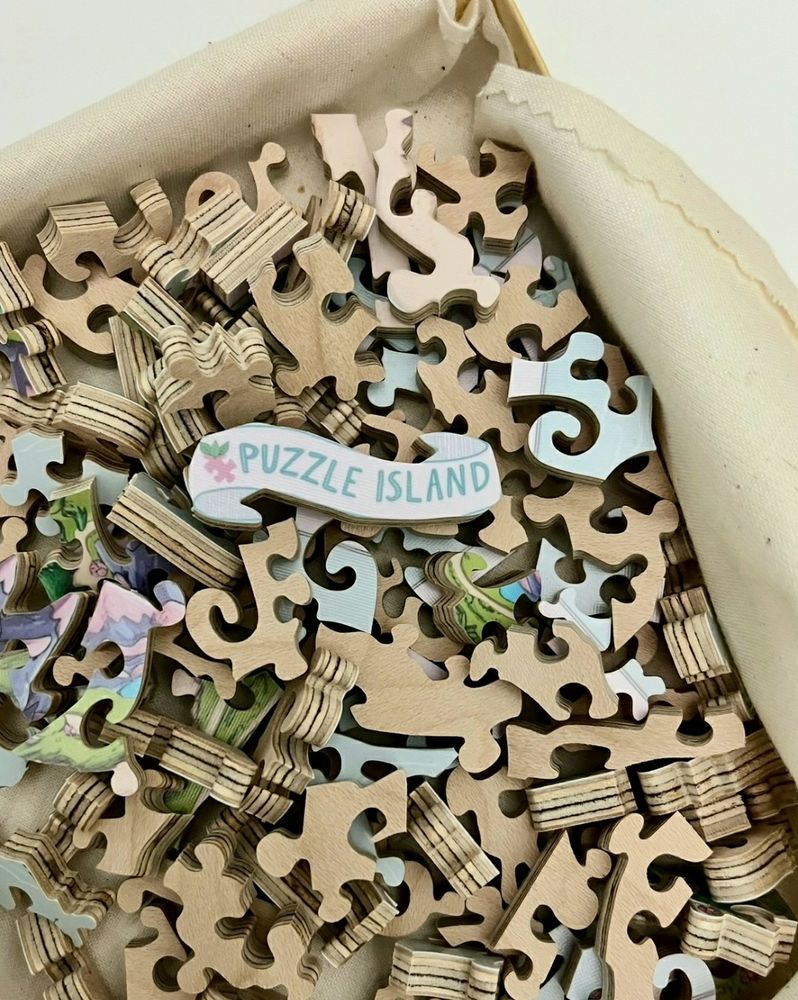 Wooden puzzle pieces in a box, with a line cut puzzle piece banner with the text "Puzzle Island" on it