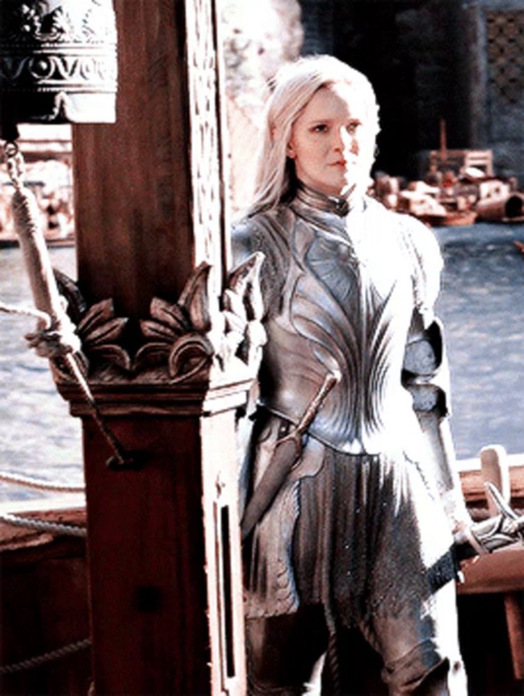 a woman in a knight 's armor stands next to a wooden post