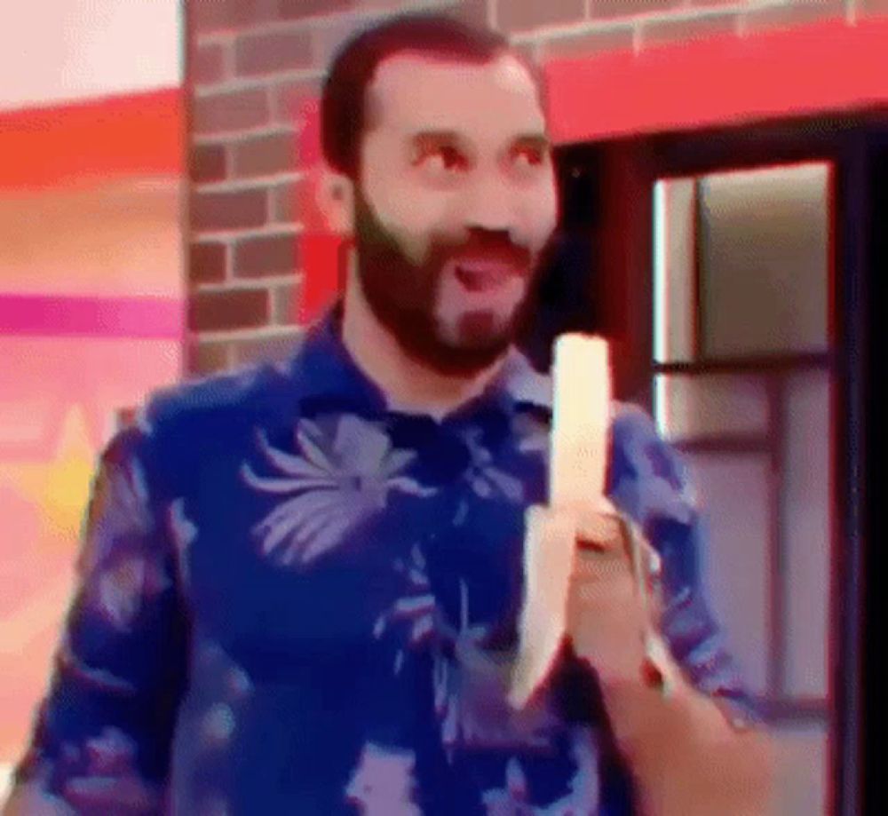 a man in a blue shirt is holding a banana in his hand