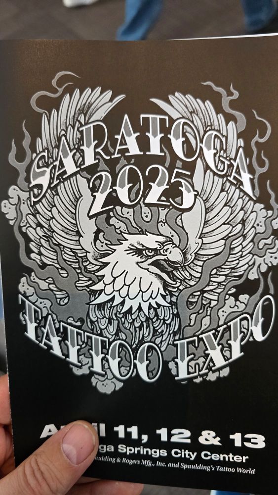 A black paper flyer with white print and drawings of an eagle in flames that says Saratoga 2025 Tattoo Expo.
