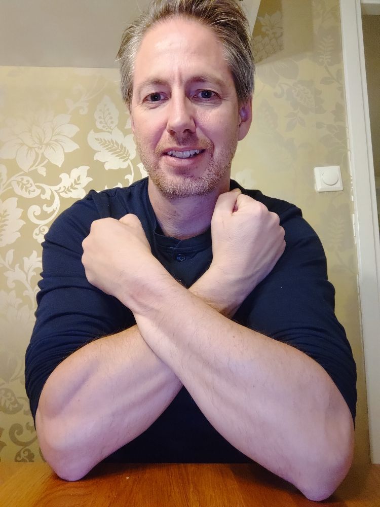 Håller underarmarna i kors.