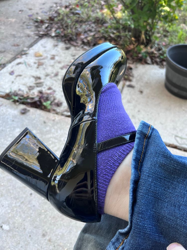 the user’s shoe, a shiny chunky heeled Mary  Jane. Underneath the shoe, the user is wearing purple ankle socks 
