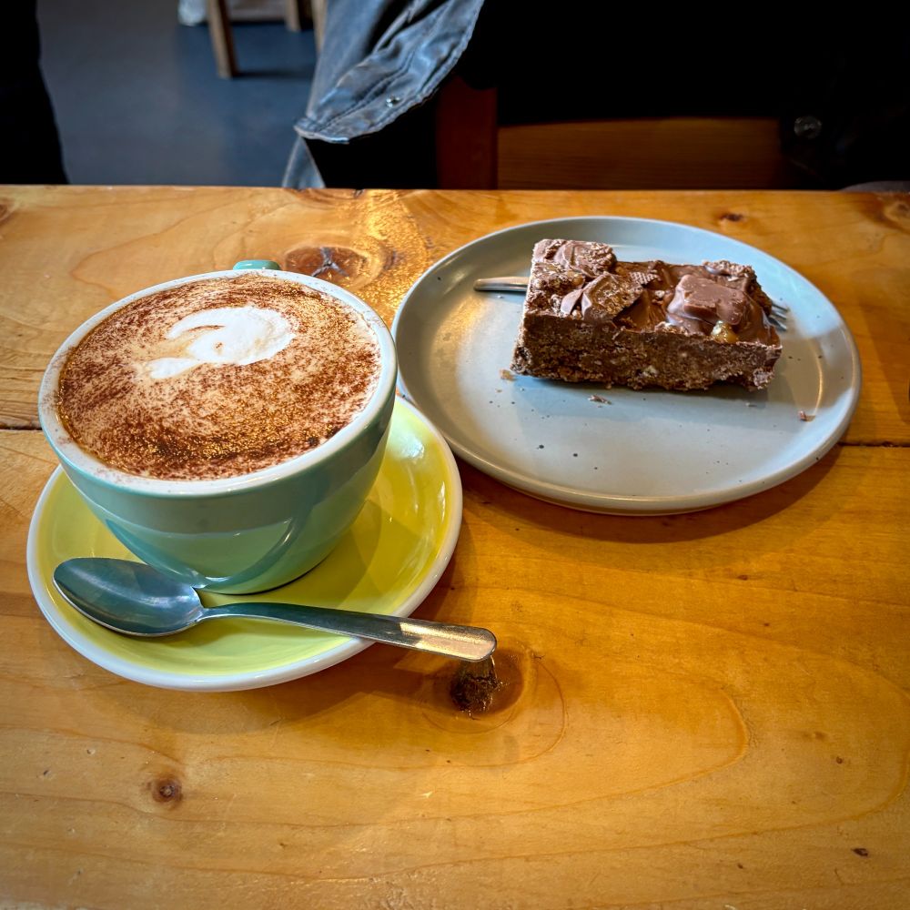 a coffee and a piece of toffee crisp tiffin on a table