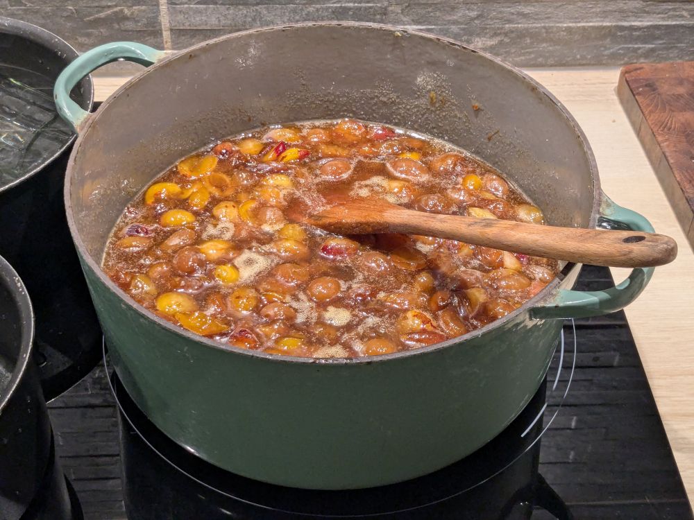 Des mirabelles cuisent dans une grande casserole en fonte 