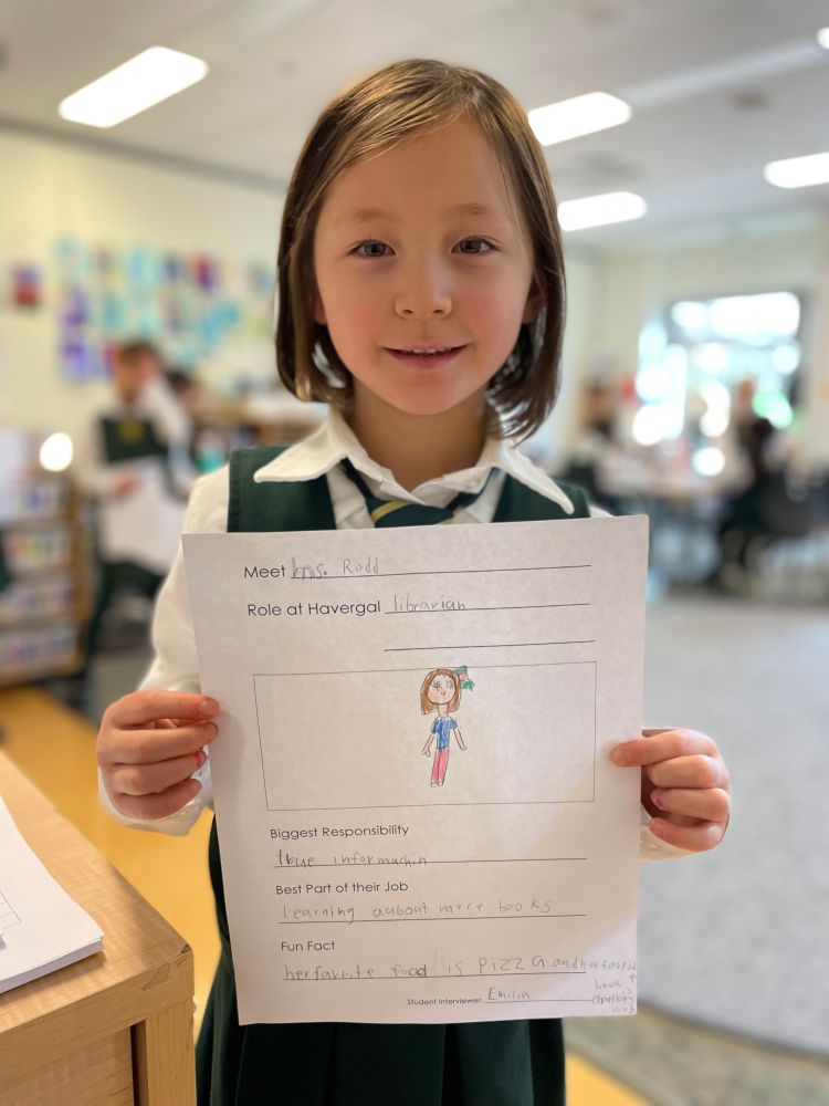A Grade 1 student holds up a sheet of paper where she has recorded what she discovered about Ms. Rodd. 