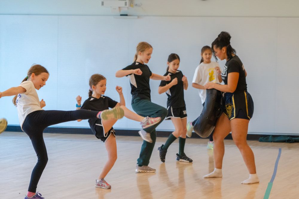 Grade 5 students practice kicking a bag that Carina is holding.