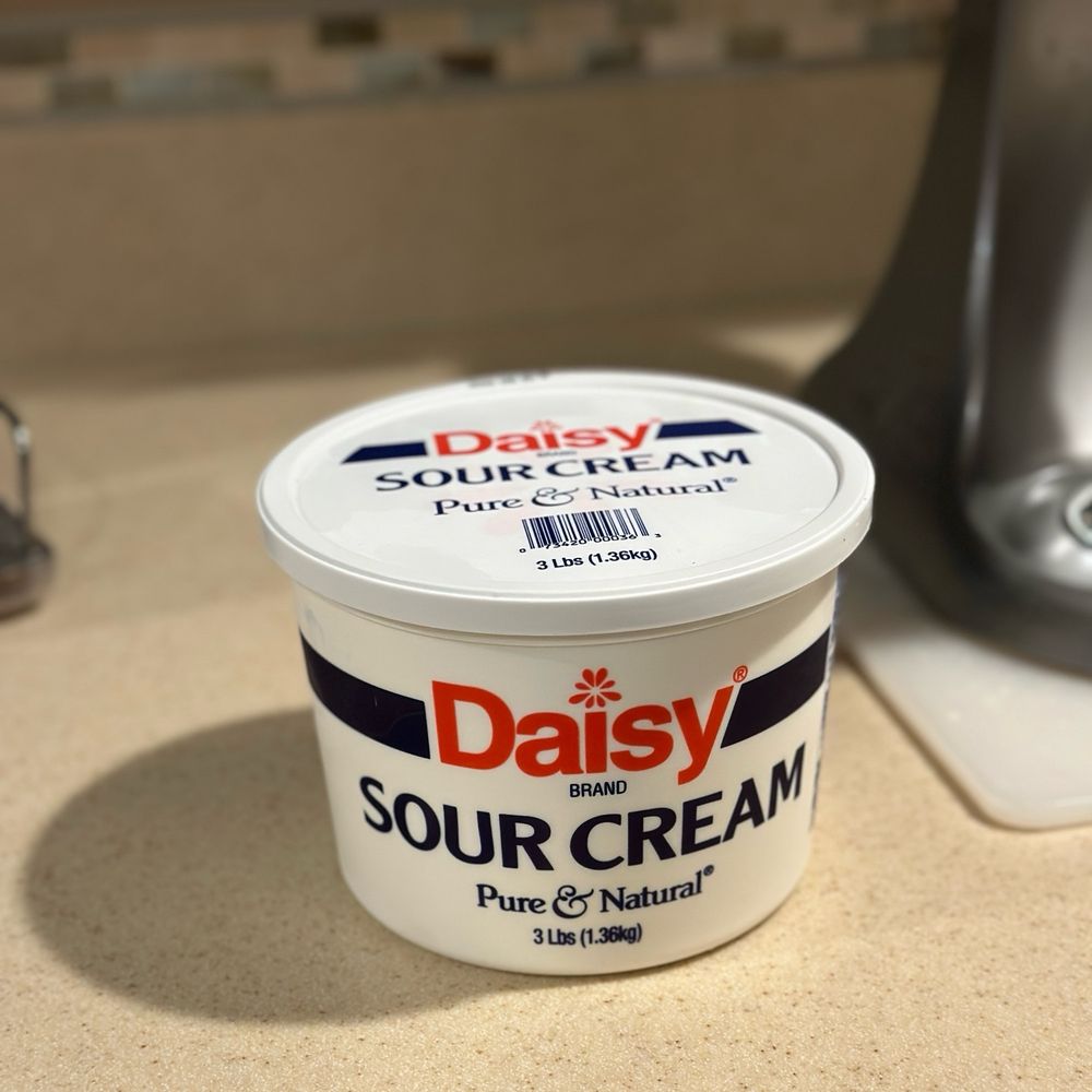 A three-pound tub of Daisy sour cream sits on a kitchen counter.