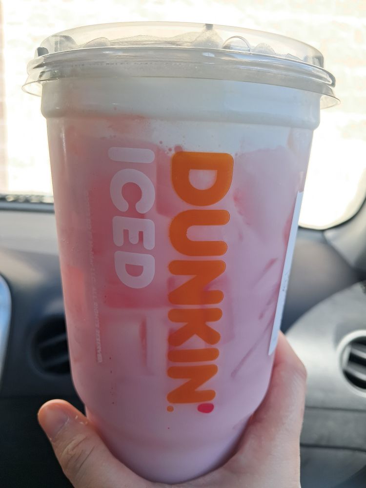 A hand holding a large strawberry day dream refresher from dunkin donuts 