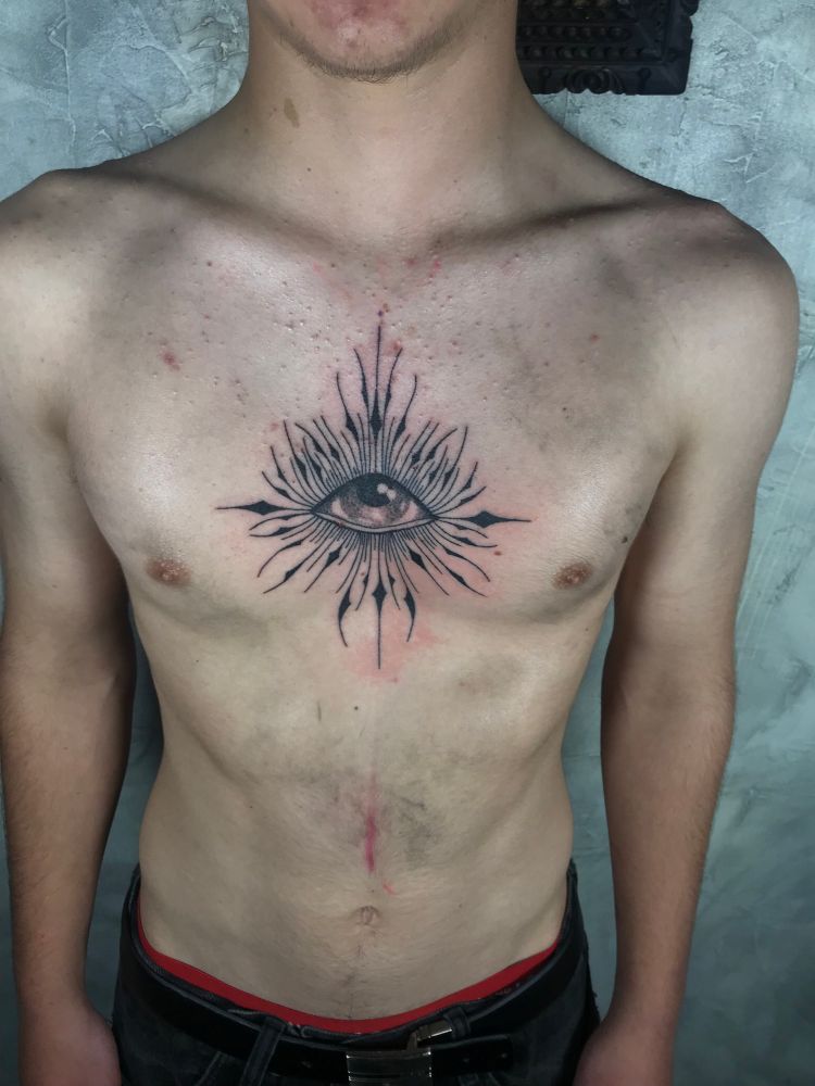 Eye tattoo in the center of the chest with spikey sharp linework. 