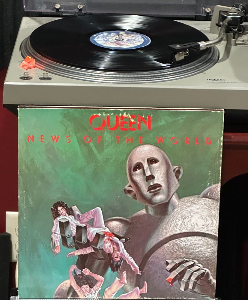 Album cover depicting a futuristic robot with band members in his hand, one with blood on his chest and blood on the robots finger. 