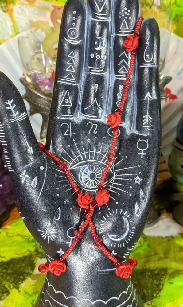 a red glass beads necklace with red rose resin beads on a hand model thing