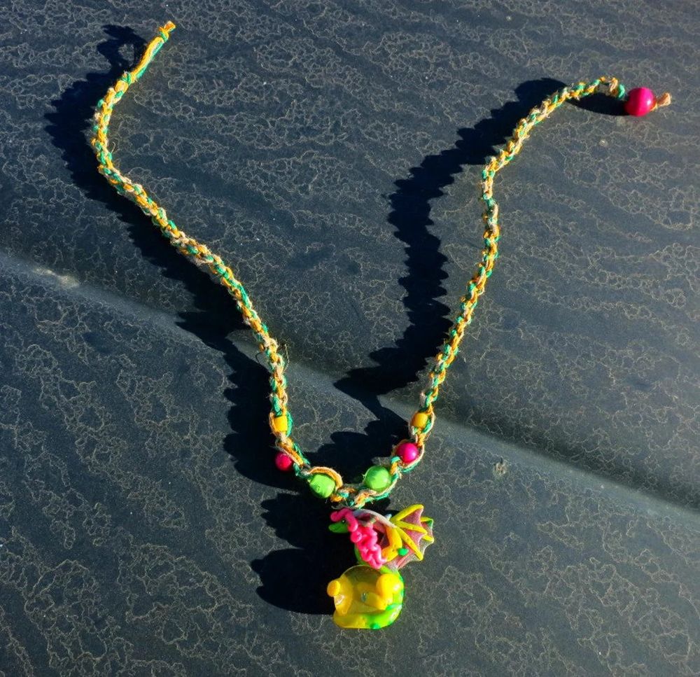 the green and yellow dragon necklace on a patterned truck hood

dragon pendant is made from sculpy and fimo, holding a marble. the necklace is dyed hemp with glass and wood beads