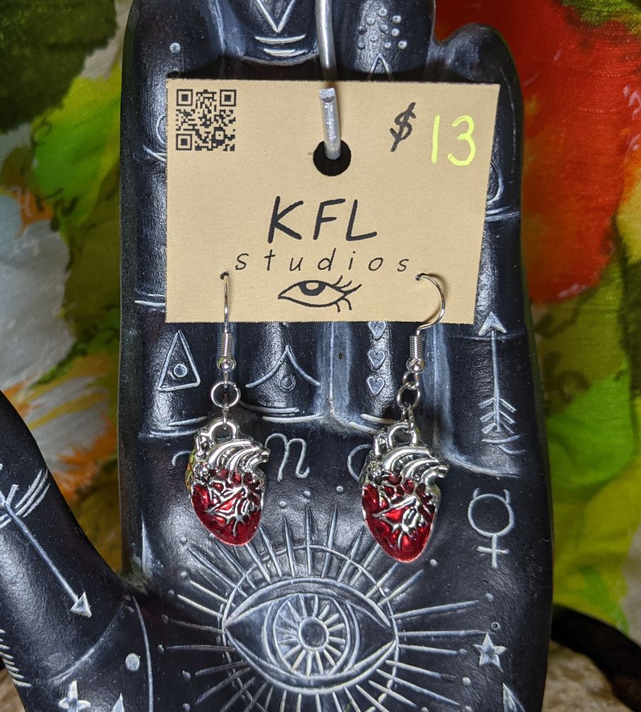 a pair of red and silver anatomical heart earrings on stainless steel fish hooks