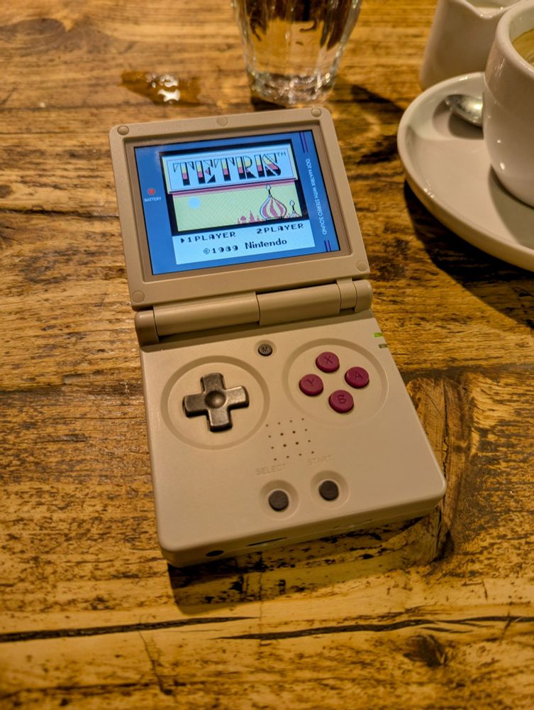 Anbernic RG35XX SP with the Tetris menu screen lying on a coffee table.
