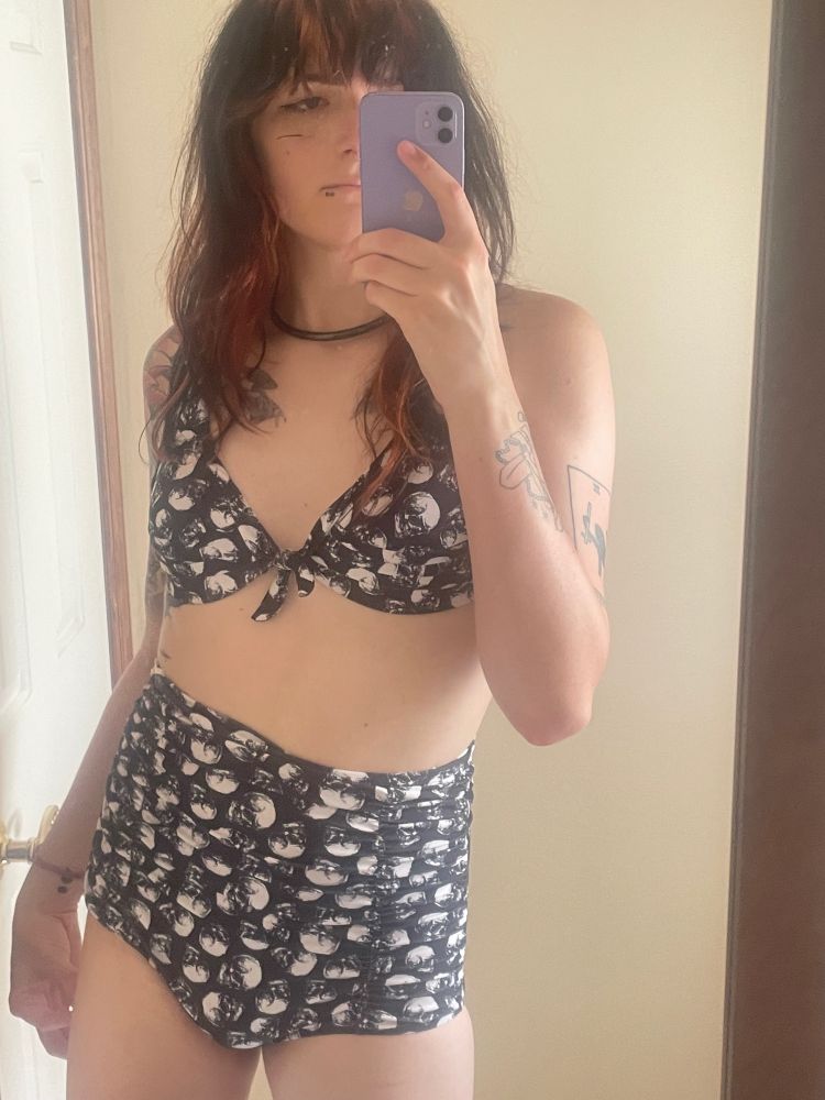 a mirror photo of a trans woman in a skull bikini. she looks kinda wacky with it