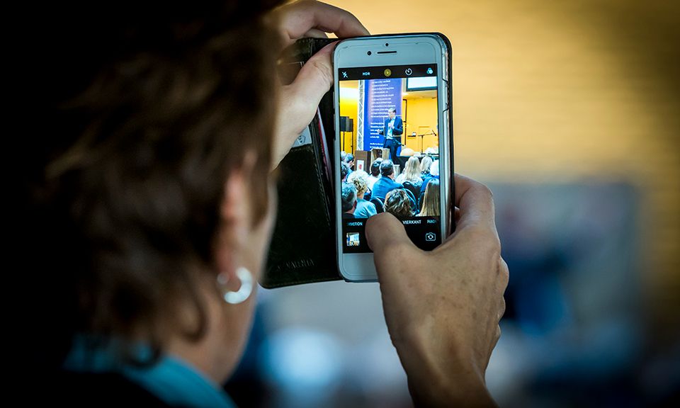 Persoon houdt smartphone in de lucht om een foto te maken.