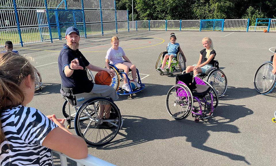 Kinderen doen mee aan rolstoelbasketbal.